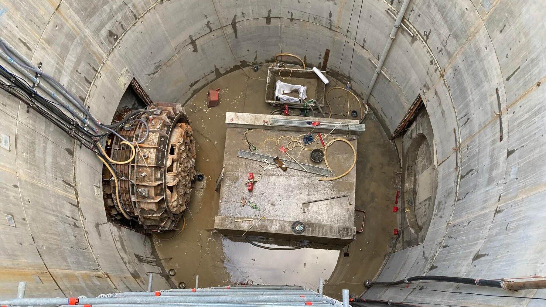 Circular tunnel made of concrete segments. Underneath, the cutting wheel is repaired under atmospheric conditions.